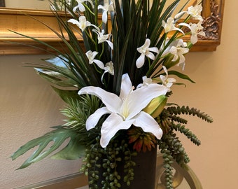 Arreglo floral tropical moderno: orquídeas, lirios y suculentas en jarrón color carbón.