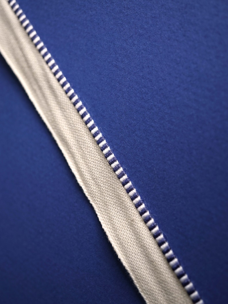 May include: A close-up of a white fabric with blue and white stripes. The fabric is against a solid blue background.