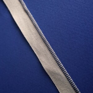 May include: A white ribbon with a gray trim on a blue background.