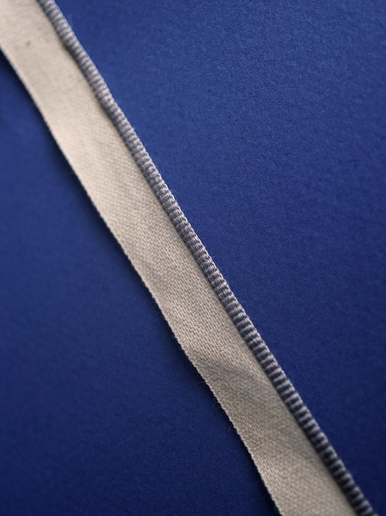 May include: A white ribbon with a gray trim on a blue background.