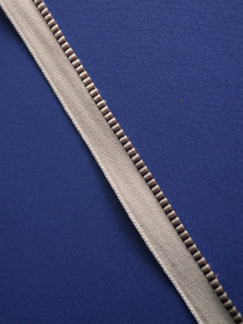May include: A white ribbon with brown stripes on a blue background.