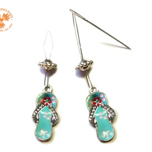 May include: A pair of silver charm earrings with a turquoise blue flip-flop charm with pink and red accents. The charms are attached to a silver bead and a silver wire.
