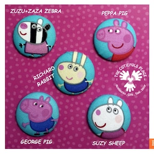 May include: Five round fabric badges featuring characters from the children's television show Peppa Pig. The badges are blue and green with white stitching. The characters include Peppa Pig, George Pig, Suzy Sheep, Richard Rabbit, and Zuzu and Zaza Zebra. The badges are labelled with the character's name and the text "The Cutiefuls Place Accessories, Gifts, Toys, Decor".