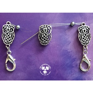 Puede incluir: Tres abalorios de búho plateados con un cierre plateado en cada uno. Los búhos están detallados con un diseño estampado. Los abalorios están enhebrados en un alambre plateado con una cuenta plateada en el medio.