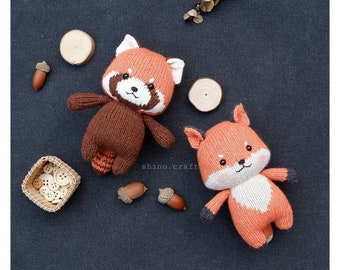 May include: Two knitted stuffed animals, a red panda and a fox, on a dark gray background. The red panda is brown with an orange face and a white muzzle. The fox is orange with a white chest and a black nose.