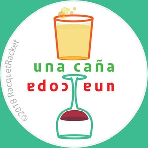 May include: A white circle with the text "una caña" in green and "edo" and "eun" in red. A glass of orange liquid sits on top of a wine glass with red wine. The text "©2018 RacquetRacket" is in the lower left corner.