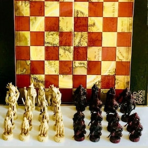 May include: A Lord of the Rings chess set with white and black pieces. The board features a map of Middle-earth. The pieces are made of plastic and are detailed with characters from the Lord of the Rings.