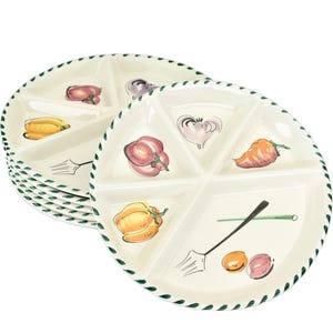 Può includere: Set di piatti da portata bianchi in ceramica divisi. Ogni piatto presenta sei sezioni, decorate con verdure dipinte a mano come peperoni e cipolle. I bordi hanno un design intrecciato verde. Anche una forchetta e un cucchiaio sono dipinti.