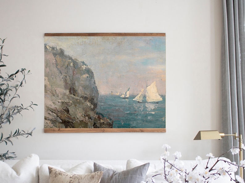 May include: A painting depicting a rocky cliffside overlooking a scene of sailboats on the water. The sky is a pale blue with touches of pink and white clouds. The water is a deep blue with whitecaps.