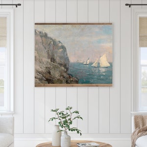 May include: A painting depicting a seascape with a rocky cliff in the foreground and sailboats in the distance. The sky is a pale blue with hints of pink and orange. The water is a deep blue with whitecaps.