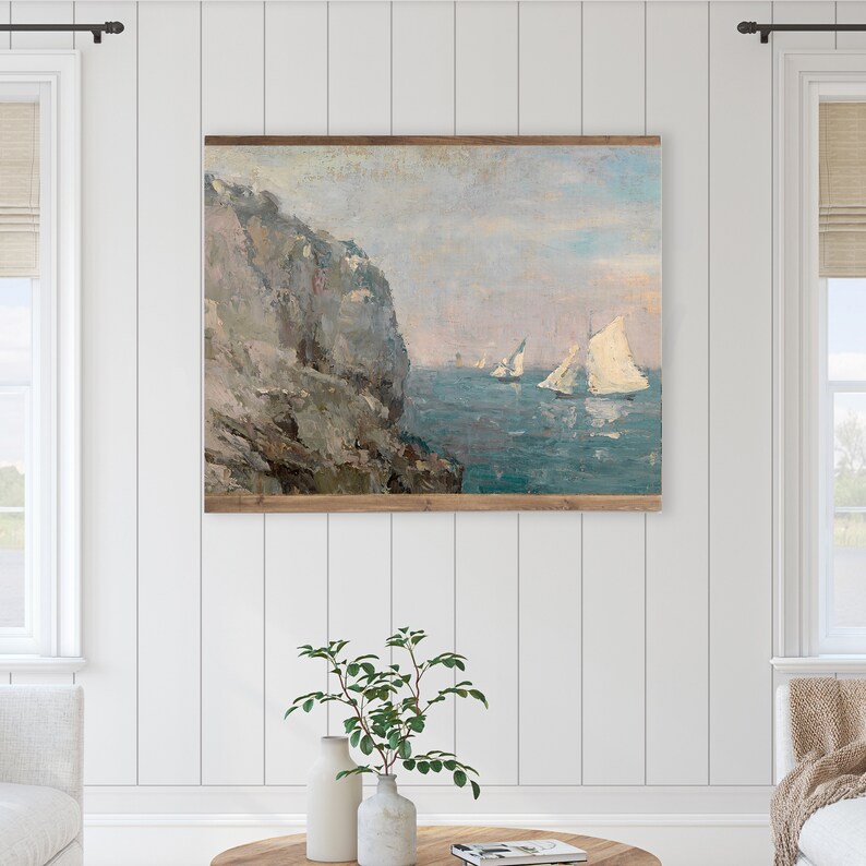 May include: A painting depicting a seascape with a rocky cliff in the foreground and sailboats in the distance. The sky is a pale blue with hints of pink and orange. The water is a deep blue with whitecaps.
