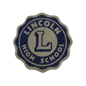 May include: A tan and blue circular patch with the text "LINCOLN HIGH SCHOOL" and a large capital "L" in the center.