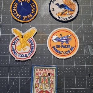 May include: Collection of vintage embroidered patches. Includes a blue and yellow RAFB Officers Open Mess patch, a John James Audubon Museum patch with a bird, and a Tri-Pacer Owners' Club patch.