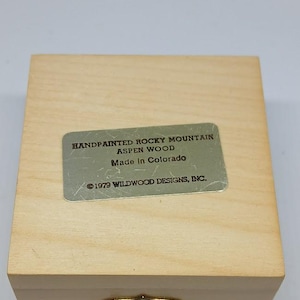 May include: A wooden box with a brass latch. The box has a label that reads "Handpainted Rocky Mountain Aspen Wood Made in Colorado &copy;1979 Wildwood Designs, Inc."