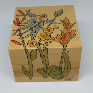 May include: A wooden box with a hand-painted design of blue, yellow, and red flowers. The box is made of light wood and has a natural finish.