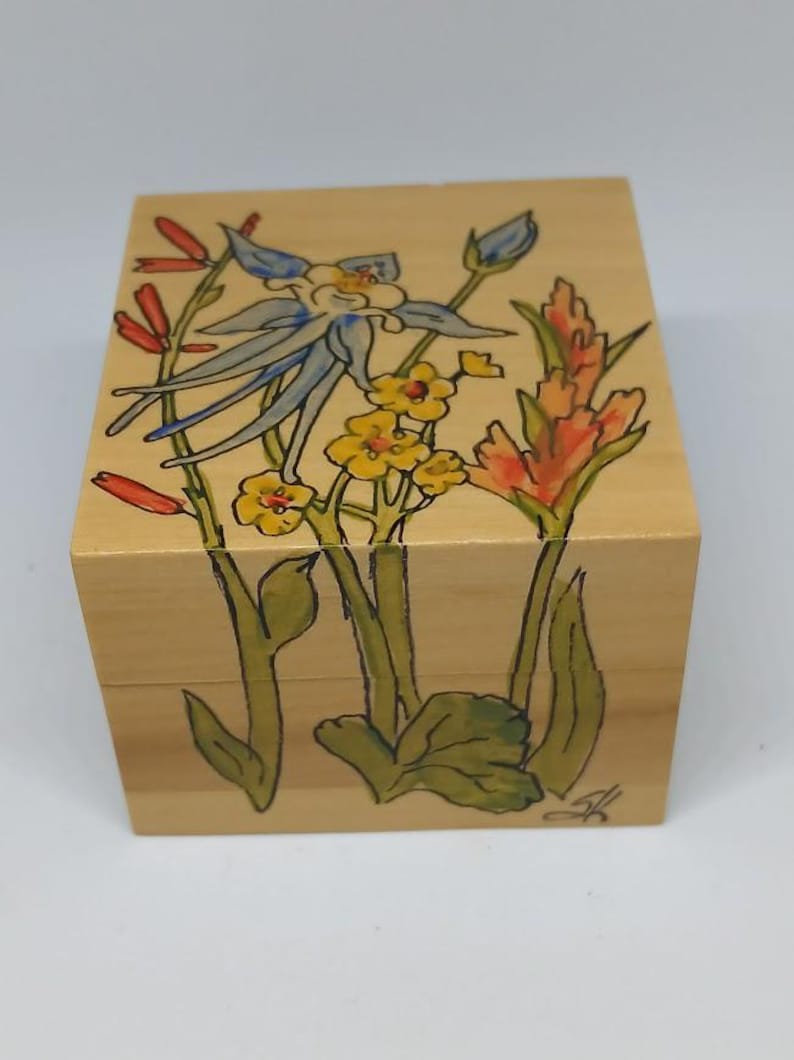 May include: A wooden box with a hand-painted design of blue, yellow, and red flowers. The box is made of light wood and has a natural finish.