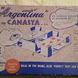 Könnte beinhalten: Vintage "Argentina" Canasta-Tablett in einer Box. Die Box ist beige mit blauen und roten Akzenten. Das Tablett ist für Karten konzipiert und trägt die Aufschriften "Draw card easily" und "Discard neatly".