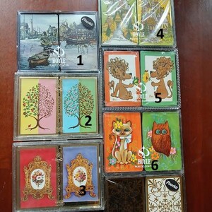Selección de barajas de cartas gemelas, sin abrir, en cajas de plástico originales.