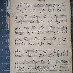 May include: A vintage sheet music page titled ETUDE with black musical notation printed on aged, off-white paper. The page features six staves of piano music, handwritten pencil notes on the left edge, and a copyright notice at the bottom.