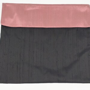 May include: A rectangular fabric pouch featuring a dark charcoal gray main body and a contrasting dusty rose pink fold-over flap. The material has a subtle, textured, slubbed appearance characteristic of raw silk, with a smooth, matte finish.