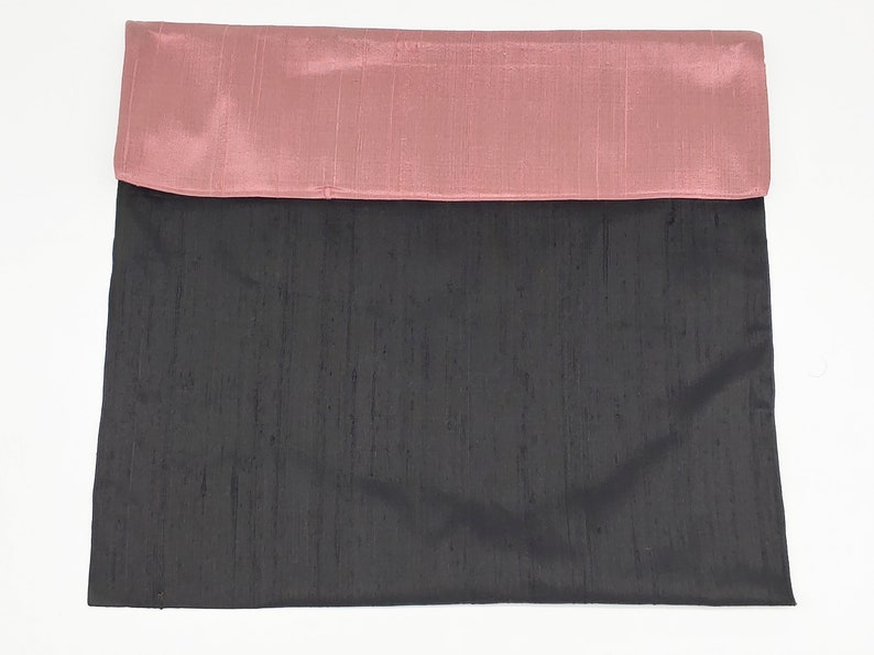 May include: A rectangular fabric pouch featuring a dark charcoal gray main body and a contrasting dusty rose pink fold-over flap. The material has a subtle, textured, slubbed appearance characteristic of raw silk, with a smooth, matte finish.