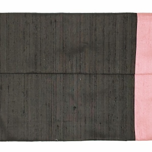 May include: A rectangular clutch bag featuring a dark charcoal gray main body with a visible slubbed texture and a contrasting solid light pink vertical panel on the right side. The design is simple and flat with a horizontal fold line across the center.