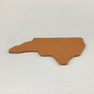 Puede incluir: Un recorte de cuero marrón del estado de Carolina del Norte.