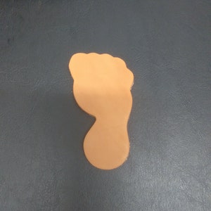 May include: A tan leather cutout of a footprint.