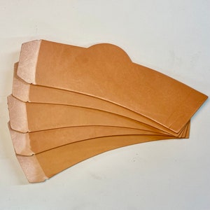 May include: Five brown leather cup coasters, stacked on top of each other. The coasters are curved to fit around a cup.