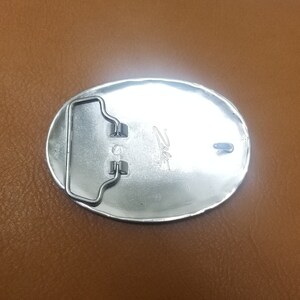 Puede incluir: Hebilla de cintur&oacute;n ovalada de plata con un bucle de metal y la palabra "Zito" grabada en la parte posterior.
