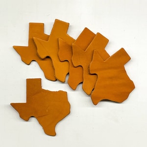 May include: Six brown leather Texas state outline cutouts. The cutouts are arranged in a cluster, with one cutout at the bottom of the image.