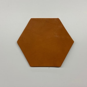 May include: A hexagonal brown leather coaster.