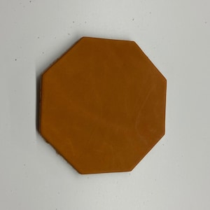 May include: A brown leather octagon-shaped coaster.