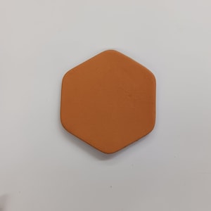 May include: A hexagonal orange coaster made of leather.