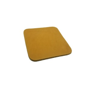 May include: A square, light brown leather coaster.