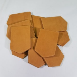 Puede incluir: Una pila de ocho parches de cuero color canela con bordes redondeados. Los parches están dispuestos en un patrón aleatorio.