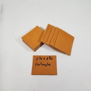 May include: A stack of 2 1/4 x 2 3/4 inch tan leather rectangles.