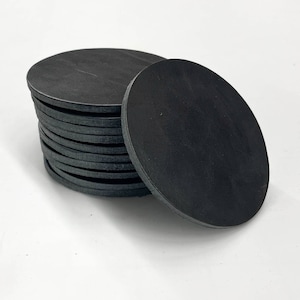 May include: A stack of black leather coasters. The coasters are round and have a smooth surface.