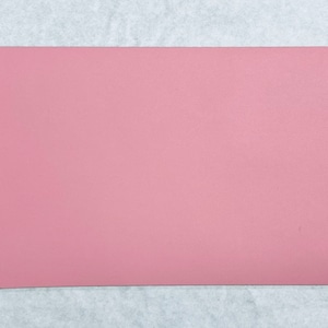 May include: A solid pink sheet of faux leather. The leather is smooth and has a subtle texture.