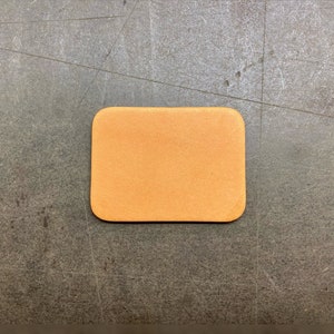 May include: A light brown leather coaster with a smooth surface.