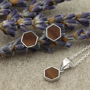 Peut inclure: Un ensemble de boucles d'oreilles hexagonales en argent et un collier avec un pendentif hexagonal en bois. Les boucles d'oreilles et le pendentif ont un incrustation en bois brun.