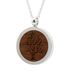 Può includere: Una collana con catena d'argento con un ciondolo rotondo con un intarsio in legno di un albero con rami spogli.