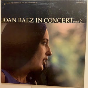 以下が含まれることがあります： ジョーン・バエズが写っているヴィンテージのレコードジャケット。シンガーソングライターのジョーン・バエズがクローズアップで写っており、タイトルは「ジョーン・バエズ・イン・コンサート パート2」と太字で書かれている。