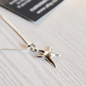 May include: A silver chain necklace with a silver starfish pendant.