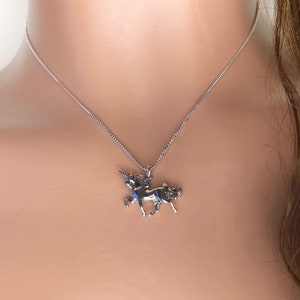 May include: A silver chain necklace with a silver unicorn pendant. The unicorn is facing right and has a horn, mane, and tail.
