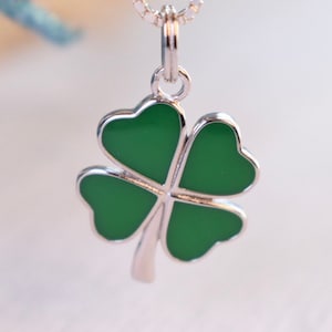 May include: A silver necklace with a green four-leaf clover pendant.