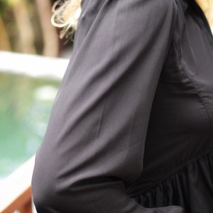 May include: A black long-sleeved blouse with a gathered waist and puffed sleeves.