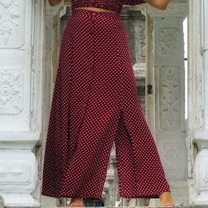 May include: A red maxi skirt with white polka dots and a button-up front. The skirt has a side slit and is made of a lightweight fabric.