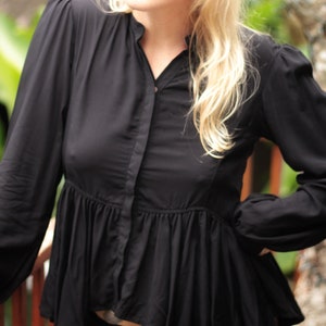 May include: A black long-sleeved blouse with a ruffled hem and a button-up front.
