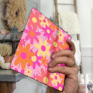 May include: A pink and orange floral patterned notebook cover with a white background. The cover has a modern, retro design.